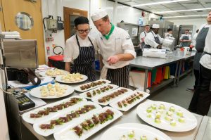 Image of a lecturer and student chef in the kitchen working with food