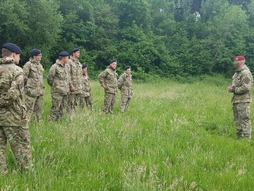 Group of cadets in full uniform receiving instructions in a field