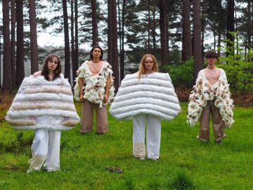 Students wearing fashion designs in a forest