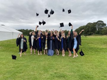 Students throw their graduation caps in the air
